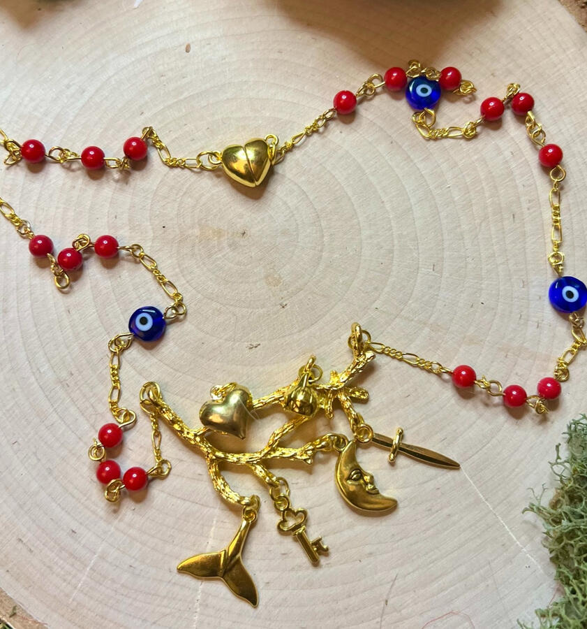 Our rendition of the Cimaruta charm, made in gold tone metal with charms hanging from a golden branch, on a rosary style chain with red coral and blue glass Nazar eye beads, finished with a magnetic heart clasp